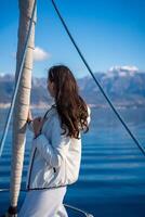 Portrait of young woman on bow of the yacht during sailing in the morning in winter time in Adriatic sea, yacht life and yachting concept. High quality photo