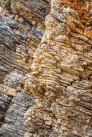 Layered rock texture in Budva, Montenegro. Sedimentary rocks with rugged surface of gray and brown. Natural formation of layers and cracks, geological structure. High quality photo