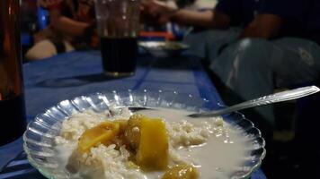 Close-up of a bowl of rice pudding with mango slices and coconut milk. photo