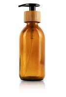 Brown glass bottle with dispenser and wooden stopper cap. Isolated on white background. Eco container for cosmetics. A container with a straw inside and a button for a pump for gel, lotion or shampoo photo