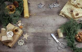 Gift wrapping for Christmas and New Year. Wooden background with place for text. Gift in craft wrapping paper. Prepare for the holiday. Copy space. photo