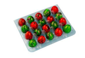 Box with colored quail eggs isolated on white background. Easter egg of red and green color in a blue package. Easter food. photo