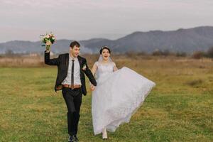 A bride and groom are running through a field with a bouquet in the bride's hand photo