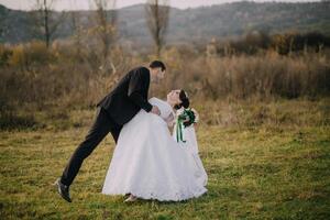 A bride and groom are playing in the grass. photo
