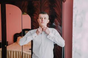 A man is getting dressed in front of a mirror. photo