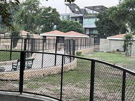 a park with a fence and benches in front of a building in Lahore on 10-10-2024 photo