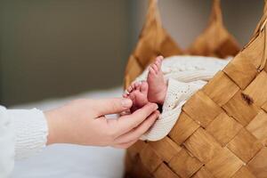 A tender close up of a babys tiny feet resting in a woven basket while an adult hand gently holds them, showcasing warmth, love, and care. photo