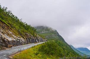 Dramatic view road across of Rocky Mountain in Norway with clouds and fog. High quality photo.Copy space. photo