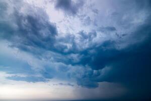 Dark stormy sky dominates, with hints of light edging through clouds photo