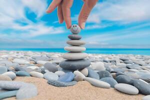 Balanced stone stack with smiley stone under tranquil blue sky photo