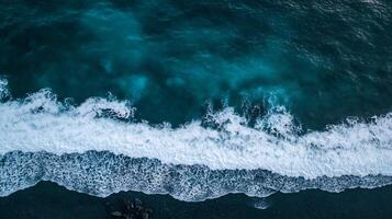 Drone View of Ocean Waves Crashing Onto Pebble Beach on a Sunny Day photo