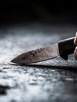 Close-up of a sharp kitchen knife on a dark textured surface with dramatic lighting for culinary themes photo