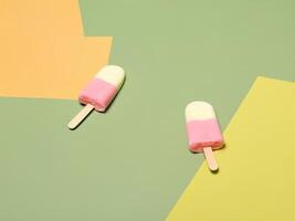 Two strawberry and vanilla ice cream popsicles lying on colorful background photo
