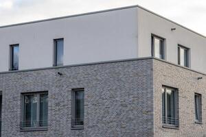 Modern residential building showing gray brick facade and white plaster upper floor photo