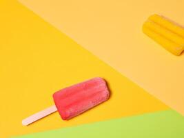 Two colorful ice cream popsicles resting on a vibrant multicolored background photo
