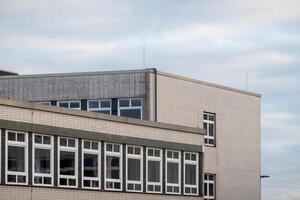 Modern building exterior with multiple windows and cloudy sky photo