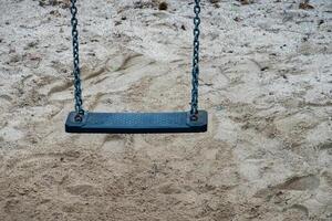 Empty swing hanging above sand in playground waiting for children photo