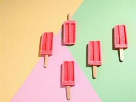Five pink ice cream popsicles on colorful background creating summer mood photo
