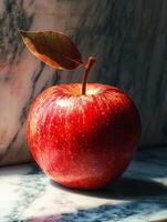 A red apple sitting on a marble counter photo