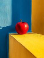 A red apple sits on a yellow and blue wall photo