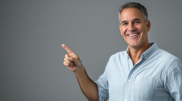 Middle-aged man smiling and pointing in casual shirt against gray background photo