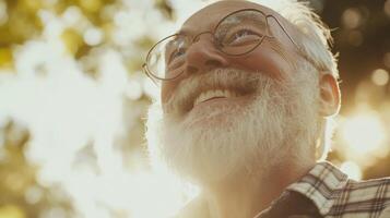 Elderly man with beard smiling outdoors in sunshine and nature backdrop photo