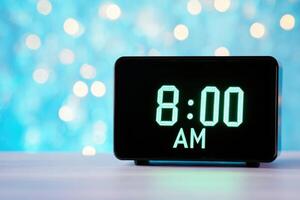 Black digital alarm clock displaying 800 AM against a futuristic metallic background with soft blue neon light photo