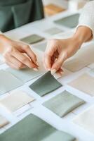 Fashion designer arranging fabric swatches in muted green and gray tones on a vision board in a contemporary workspace photo