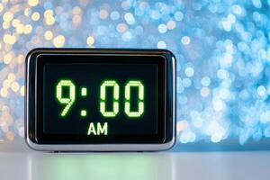 Digital clock displaying 9 00 AM with glowing green numbers against futuristic metallic background and soft blue neon light photo
