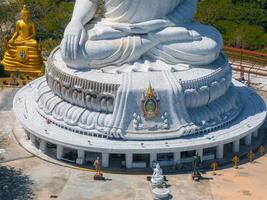 The base of the Big Buddha statue in Phuket, Thailand, features intricate details, smaller sculptures, pathways, and lush greenery in a serene setting. photo