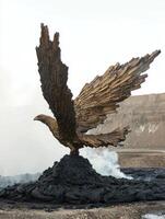Bronze eagle sculpture on a pile of dark material photo