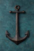 Rustic bronze anchor on dark teal background photo