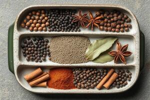 Various aromatic spices and herbs beautifully arranged in a compartmentalized dish for culinary delights photo