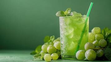 Refreshing green grape juice with ice, mint, and straw on green background photo