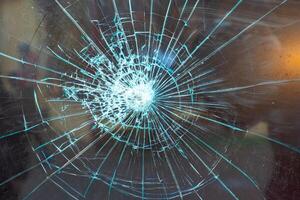 Cracked glass surface with intricate patterns illuminated by light, showcasing a dramatic burst effect photo