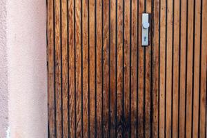 Wooden door with vertical slats and lock in a warm-toned structure during daylight photo