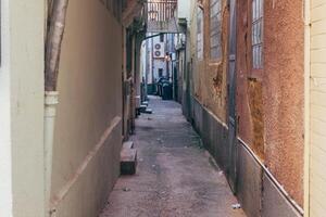Narrow city alleyway with textured walls and scattered refuse during late evening hours photo