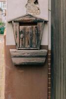 Old wooden mailbox mounted on a weathered wall with rustic charm photo