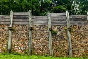 Reconstruction of ancient fortification featuring wooden palisades and stone wall in a forested area photo