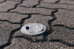 Coin resting on a textured pavement with cracked surface in an urban environment during daylight photo