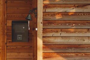 Rustic wooden wall with a vintage bell and decorative mailbox in a warm outdoor setting photo