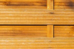 Wood paneling with warm tones and textured lines in a natural setting during daylight hours photo