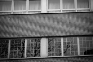 Textured architectural facade with windows reflecting trees on an overcast day in an urban setting photo