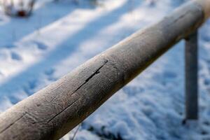 Frost-covered wooden railing in a tranquil winter landscape under soft sunlight photo