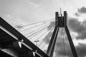 Suspension bridge towers under cloudy sky at sunset with cables and structural details highlighted photo