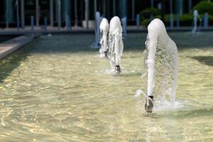 Water fountains create playful displays with bubbles at a modern urban location during sunny day photo