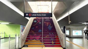 a stairway with colorful stairs and a sign. A view inside of Blok M MRT Station in Jakarta photo