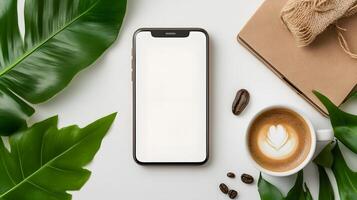 Smartphone with a blank white screen placed near a cup of coffee and an open notebook, ideal for productivity themes photo