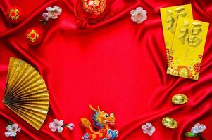 Chinese new year background with envelope packets or ang bao word mean blessing, red bag and ingots words mean wealth, hanging pendant dragon on red cloth background. photo