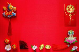 Chinese new year background with envelope packet or ang bao word mean auspicious, ingots word mean wealth, hanging pendant dragon and snake on red cloth background. photo